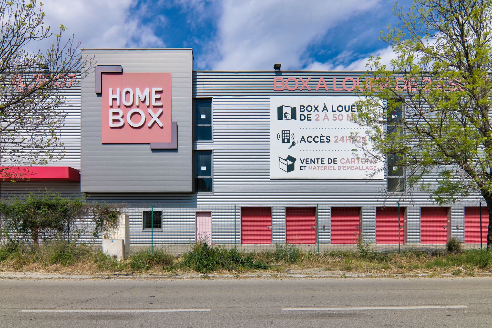 Façade du centre HOMEBOX Avignon, Chemin de Ramatuel, avec portes de box rouges et grand panneau d’informations.
